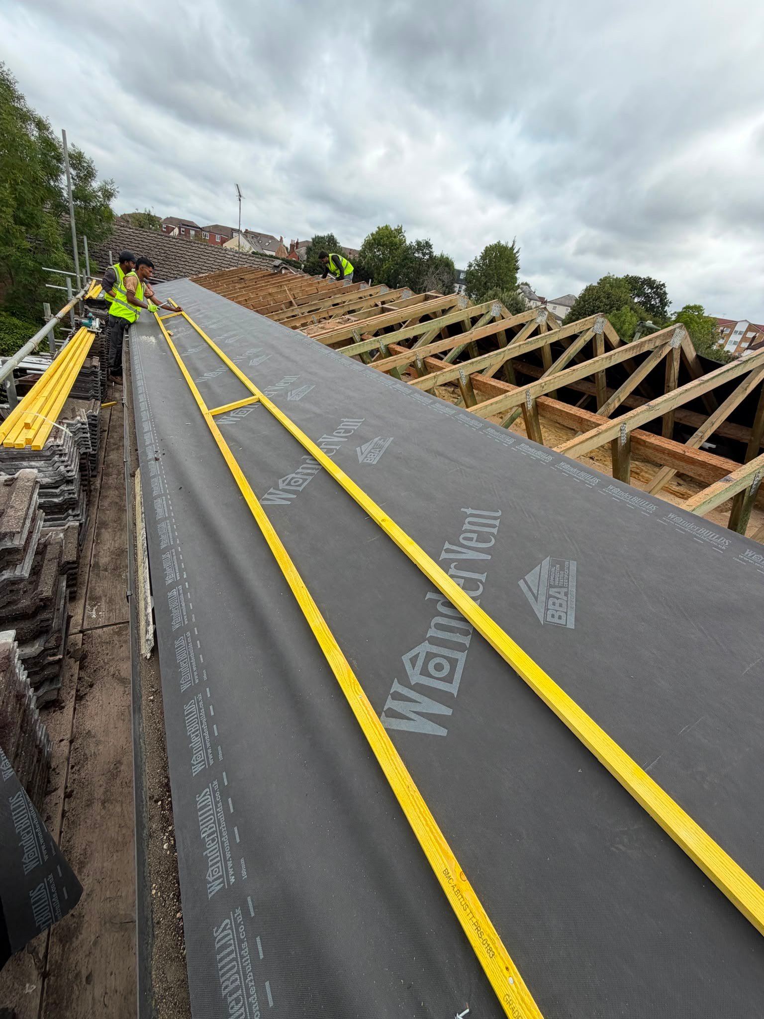 Membrane installation continuing across exposed rafters